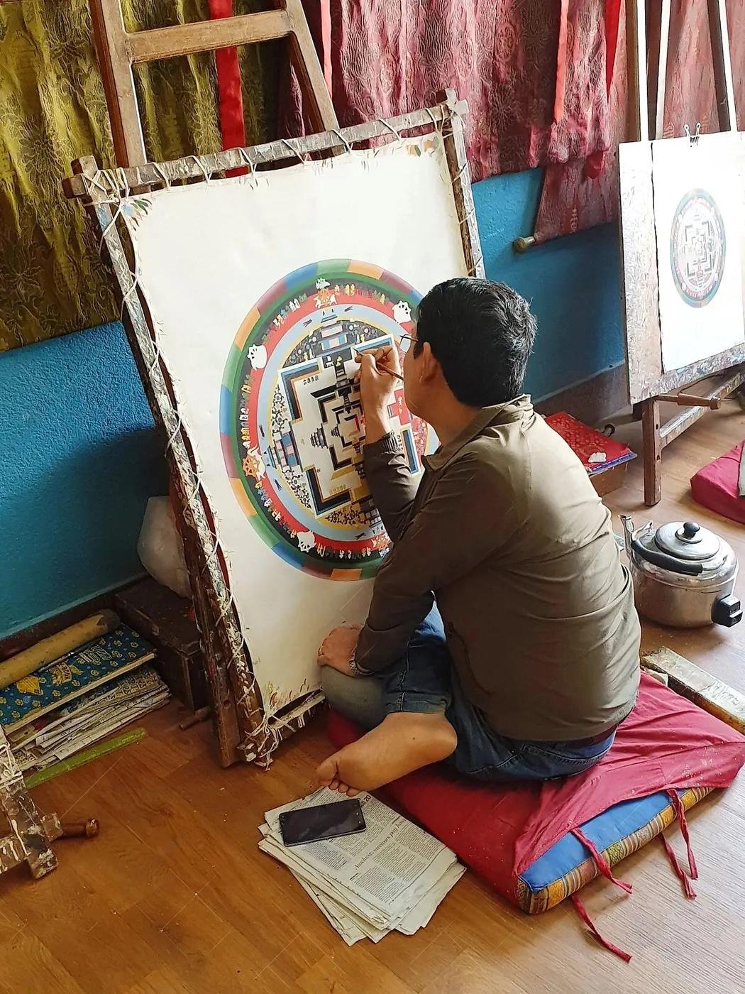 A Nepali painter at work on a large mandala in his studio.